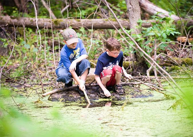 Children sitting by a swampy lake