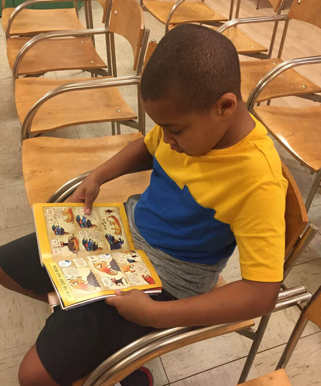 A young person reading a comic in a chair.