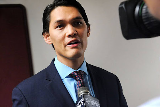 photo of Antonio Buehler in a suit talking to a camera operator who is mostly out of the image