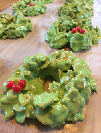 Green marshmallow and cornflake wreath cookies with three red hots as holly berries