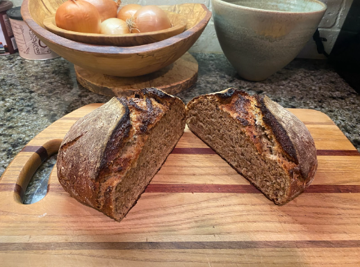 Dark multigrain loaf of bread cut open on a cutting board